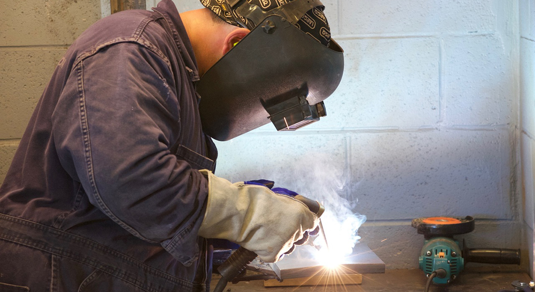 Young craftsman in the process of welding.